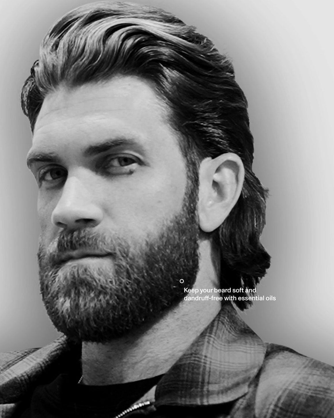 Black and white close-up portrait of a Bryce Harper with styled hair, a full beard, and a plaid shirt, with small text near the lower right side of the face.