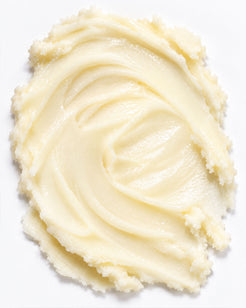 A swirl of thick, creamy pale yellow beard balm on a plain white background.